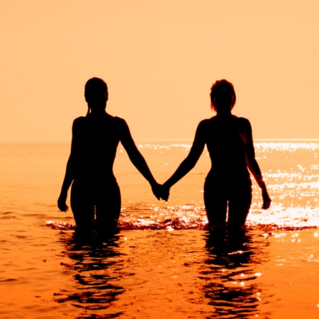 Couple walking into the sea at sunset.