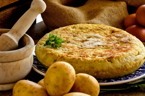 Tortilla de patata con productos para hacerla y mortero