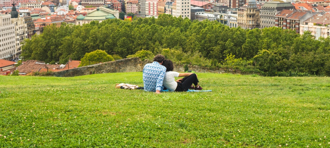 Couple watching a beautiful panoramic view of the city sitting in the park, on the hill above the Old Town