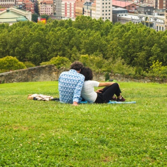 Пара любуется прекрасным панорамным видом на город, сидя в парке на холме над Старым городом