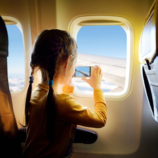 Ein Mädchen macht ein Foto durch das Flugzeugfenster