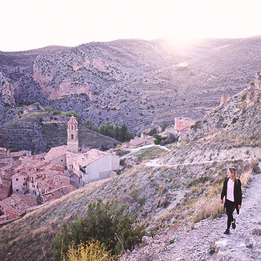 Turista paseando por una ladera con vistas al pueblo de Albarracín, Teruel