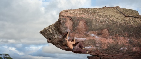 Mann klettert auf einen Felsblock in der Sierra de Albarracín in Teruel, Aragonien