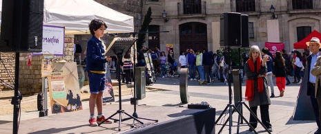 Child reading Don Quixote in front of the Barcelona Cathedral during Sant Jordi