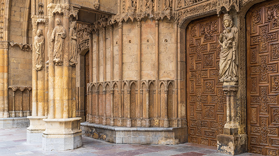 Ein großes, dunkles Holztor, das mit aufwendigen geometrischen Motiven und geschnitzten Paneelen verziert ist