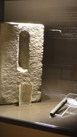 Ein massiver, beleuchteter Steinblock weist in seiner Mitte eine längliche, vertikale Vertiefung auf