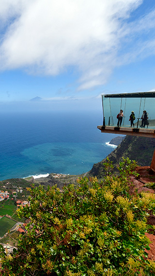 Ein Aussichtsplattform mit Wänden und Boden aus Glas ragt schwebend über den Abgrund hinaus