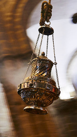 Ein großes Räuchergefäß aus Metall fliegt mit hoher Geschwindigkeit durch die Luft und hinterlässt unter den hohen Steinbögen eine verschwommene Spur