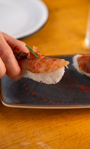 Nigiri crocante com vinagre em pó, shoyu, pargo curado, kombu, tomate em pó e jamón