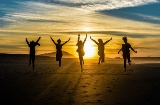 Freunde bei Sonnenuntergang an einem Strand in Galicien