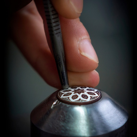 Craftsman decorating a piece using the damascene technique