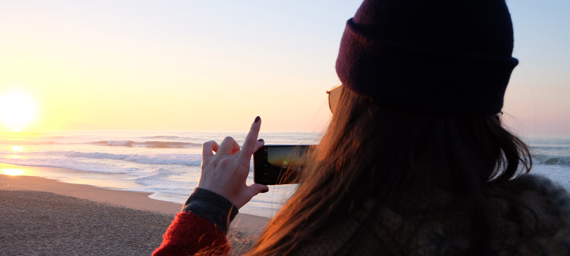 Une jeune fille prend une photo au coucher de soleil