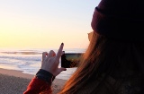 Girl taking a photograph at sunset