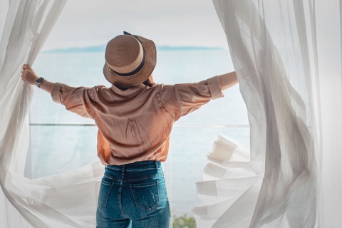 A tourist opening the curtains to their room