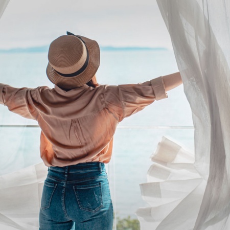 Turista abrindo as cortinas do seu quarto de hotel