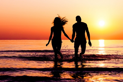 Un couple sur la plage, au coucher du soleil