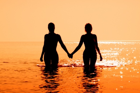 Un couple entre dans la mer au coucher de soleil