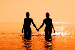 Пара заходит в море на закате