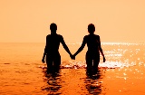 Pareja entrando en el mar durante el atardecer