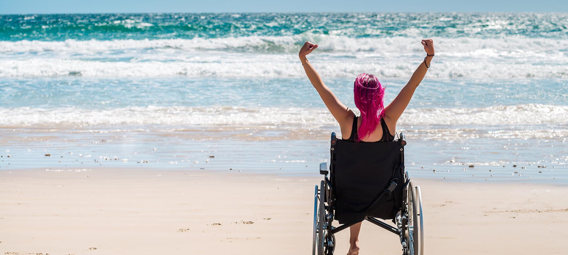 Tourist in a wheelchair enjoying the beach