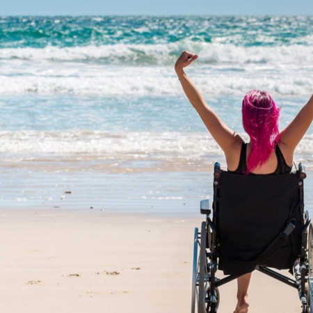 Tourist in a wheelchair enjoying the beach