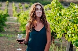 Una donna tra i vigneti con un calice di vino in mano