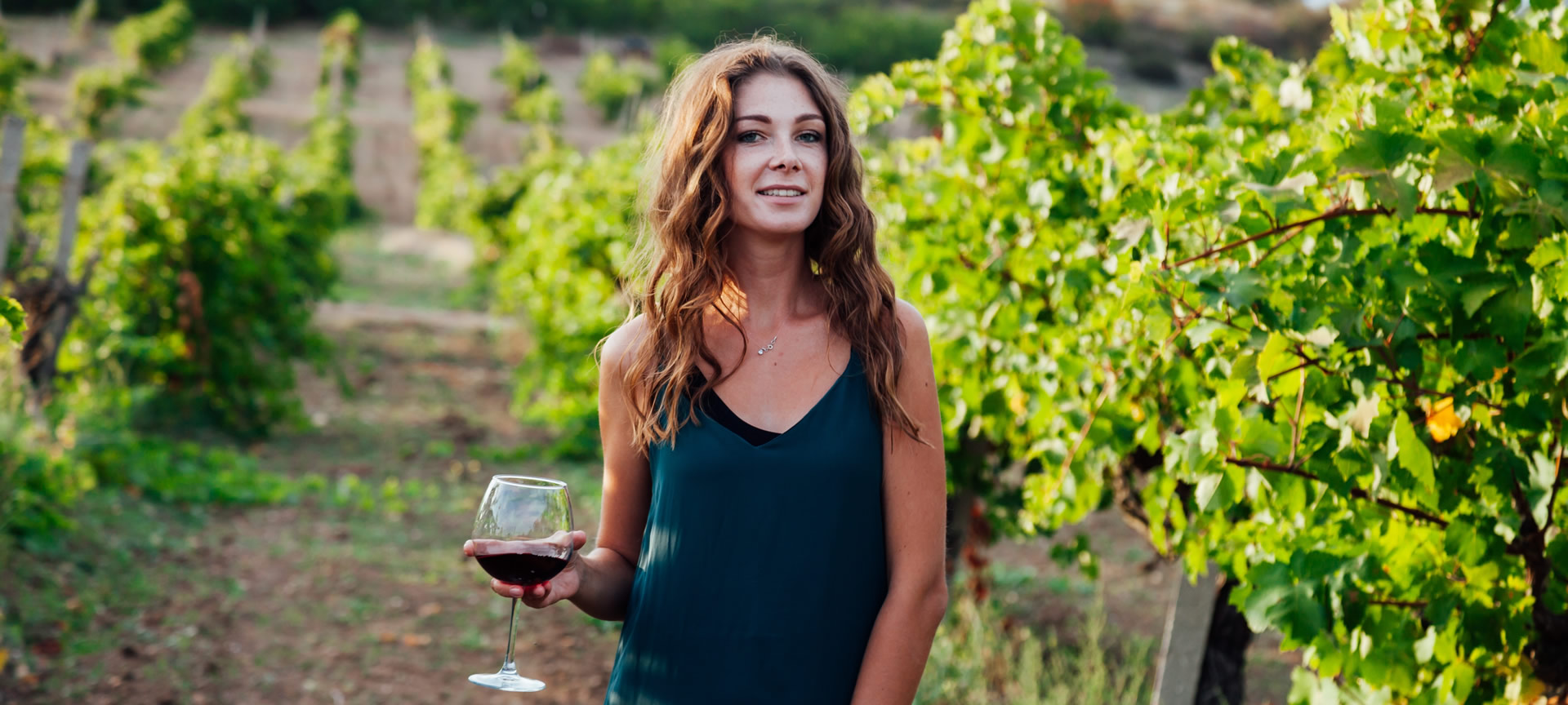 Femme parmi les vignes avec un verre de vin à la main Femme parmi les vignes avec un verre de vin à la main