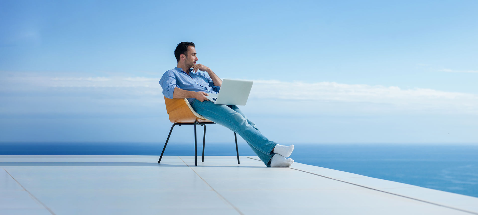 Homme travaillant sur un ordinateur portable avec vue sur la mer