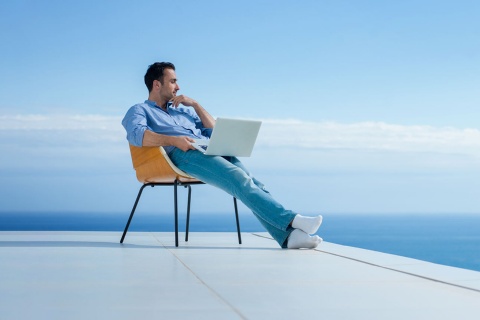  Мужчина работает с ноутбуком на фоне моря