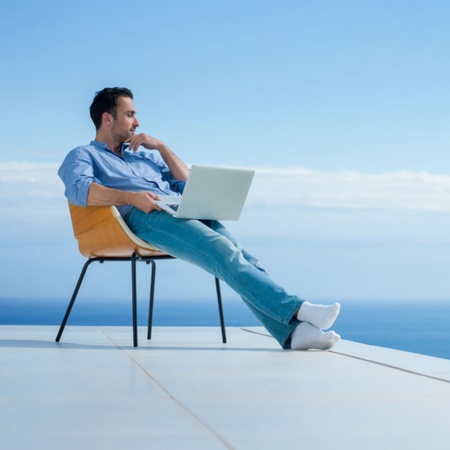 Man working on a laptop with sea views