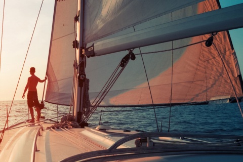 Junger Mann auf einem Segelboot bei Sonnenuntergang