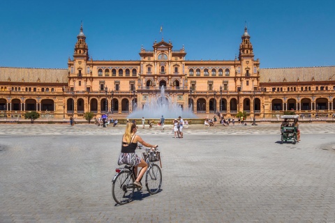 Туристы на велосипедах на площади Испании в Севилье, Андалусия