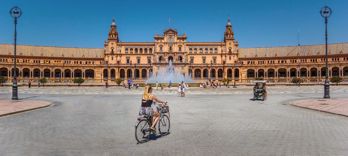 Turistas de bicicleta pela Praça de España de Sevilha, Andaluzia