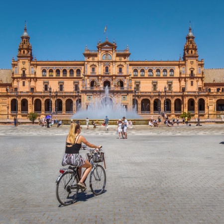 Turyści przemierzający na rowerze Plaza de España w Sewilli, Andaluzja