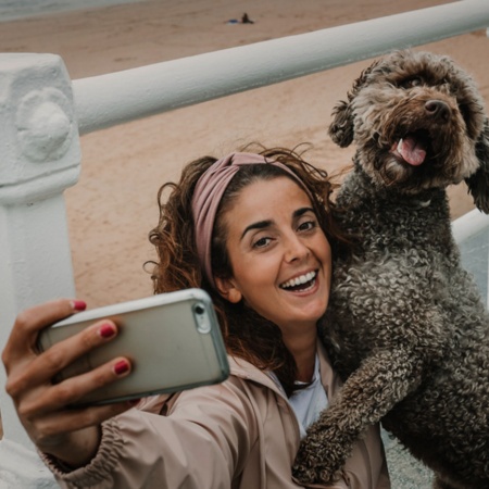 Tourist taking a selfie with their dog on a beach in Gijón, Asturias