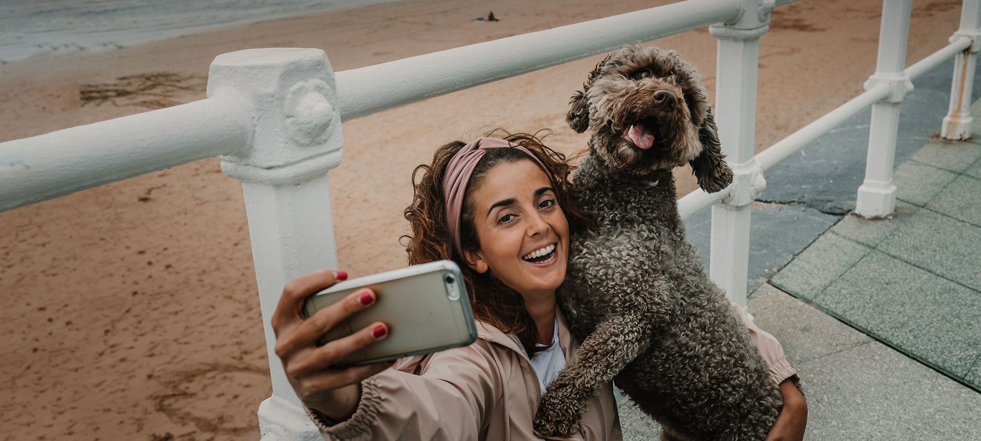  Tourist taking a selfie with their dog on a beach in Gijón, Asturias