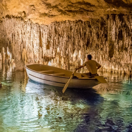 Homem numa lancha no interior das Cuevas del Drach (cavernas do dragão), em Maiorca.