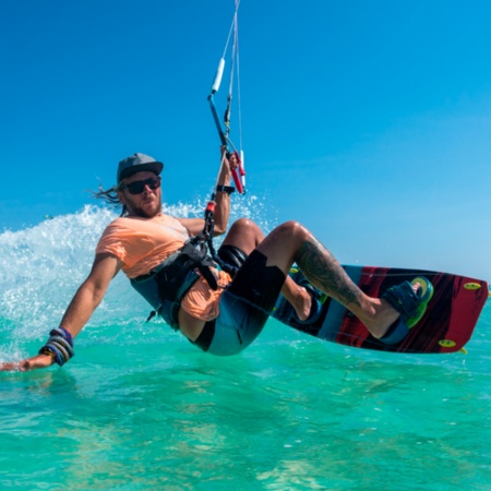 Young man kitesurfing over clear waters