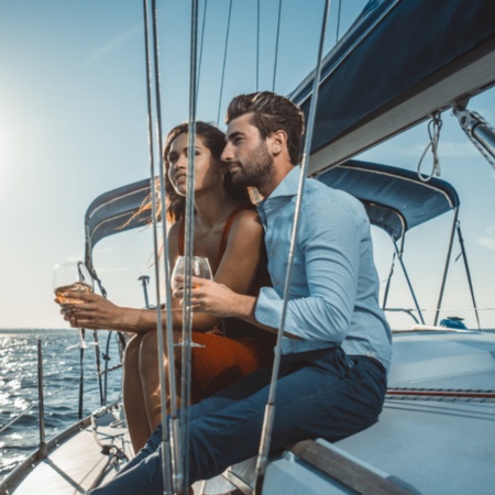 Pärchen genießt ein Glas Wein auf einem Segelboot bei Menorca, Balearen.