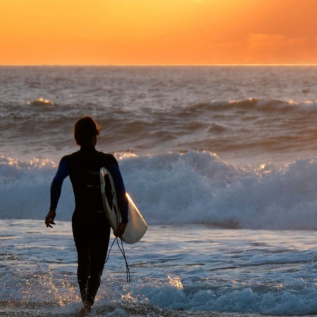 Surfista che contempla il tramonto a Fuerteventura, nelle isole Canarie