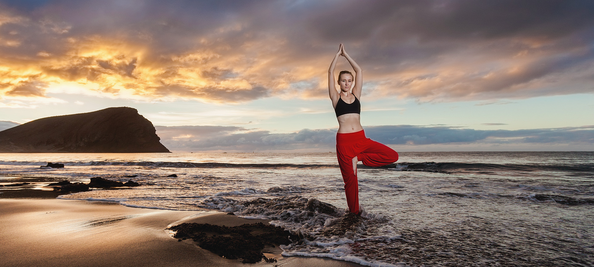 Una ragazza mentre fa yoga al tramonto sulla spiaggia di La Tejita di Granadilla de Abona a Tenerife, isole Canarie