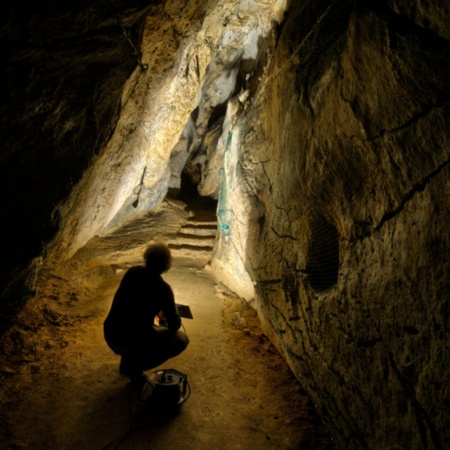 Homem iluminando representações de arte rupestre na Caverna de Chufín, em Riclones (Cantábria)