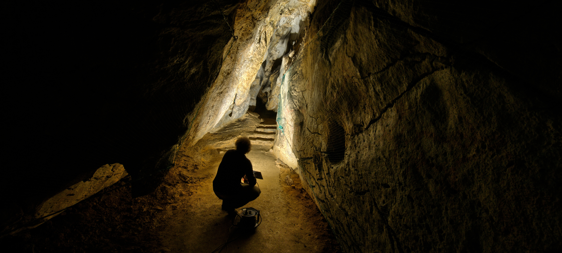 Uomo che illumina le rappresentazioni di arte rupestre nella grotta di Chufín a Riclones, Cantabria Uomo che illumina le rappresentazioni di arte rupestre nella grotta di Chufín a Riclones, Cantabria