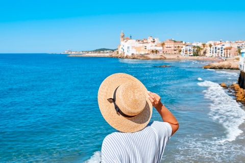 Woman looking at the sea and the church of Sant Bartomeu in Sitges