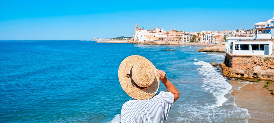 Mujer contemplando el mar y la iglesia de Sant Bartomeu en Sitges
