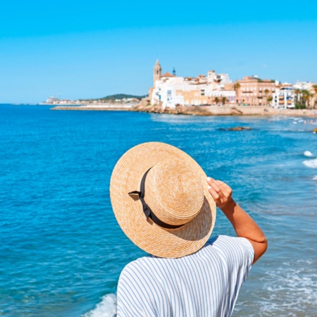 Woman looking at the sea and the church of Sant Bartomeu in Sitges