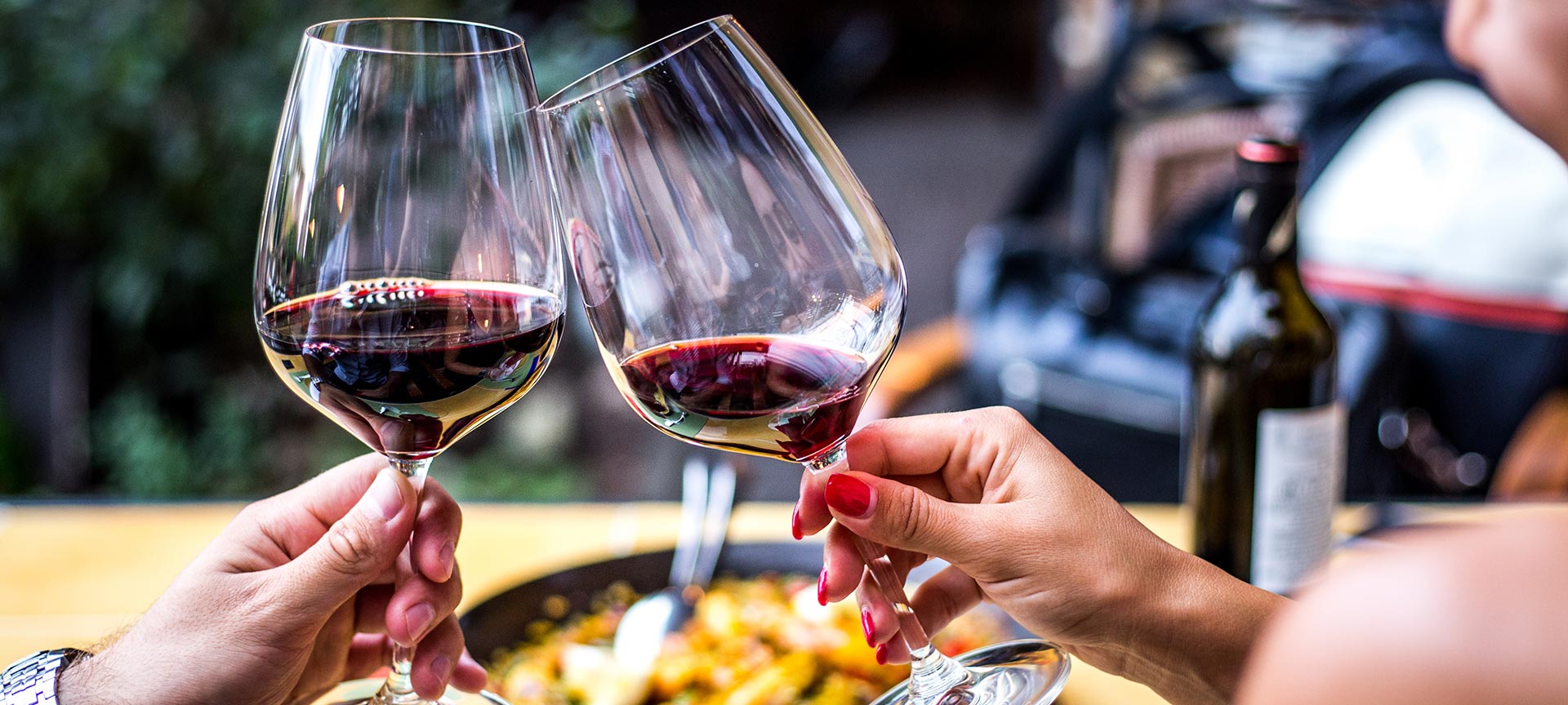Brindis con vino tinto y paella de fondo Brindis con vino tinto y paella de fondo