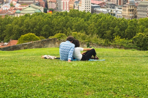 Casal contemplando uma linda vista panorâmica da cidade sentados no parque da colina sobre o Centro Histórico
