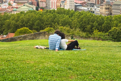 Casal observando uma bela vista panorâmica de Bilbao sentado no parque na colina acima do centro histórico