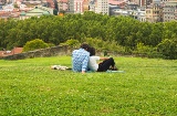 Couple watching a beautiful panoramic view of the city sitting in the park, on the hill above the Old Town